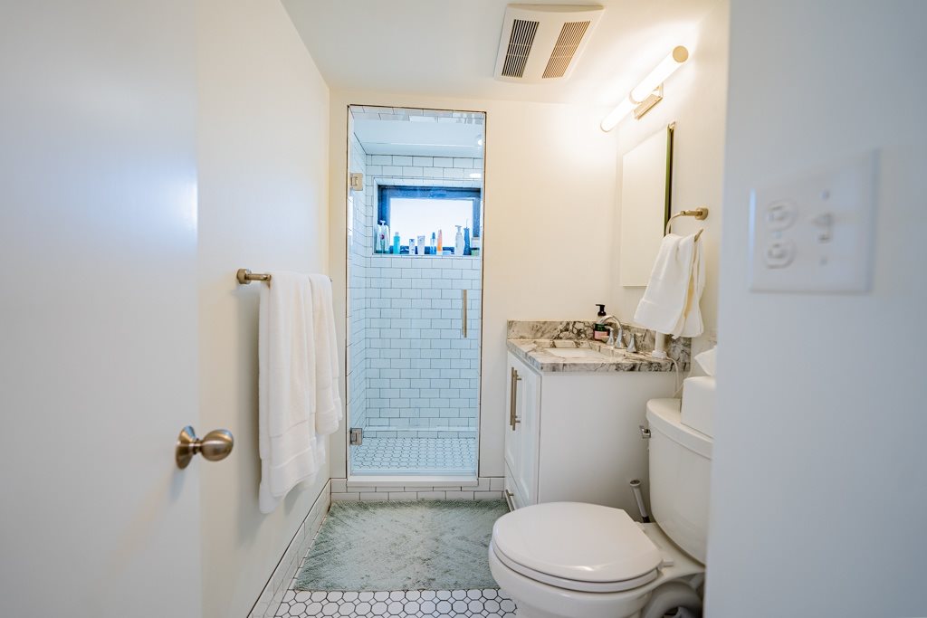 A white toilet with a marble top sits in a bathroom with a walk-in shower.